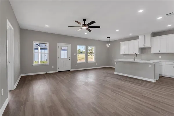 a view of an empty room with window and wooden floor