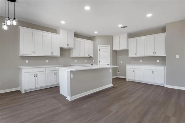 a kitchen with wooden floors white cabinets appliances and a sink