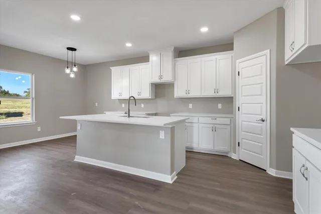 a view of kitchen with granite countertop white cabinets a sink and dishwasher with wooden floor