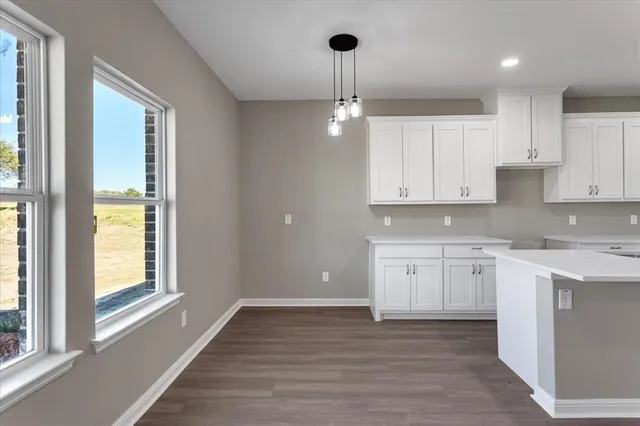 a kitchen with granite countertop white cabinets and wooden floor