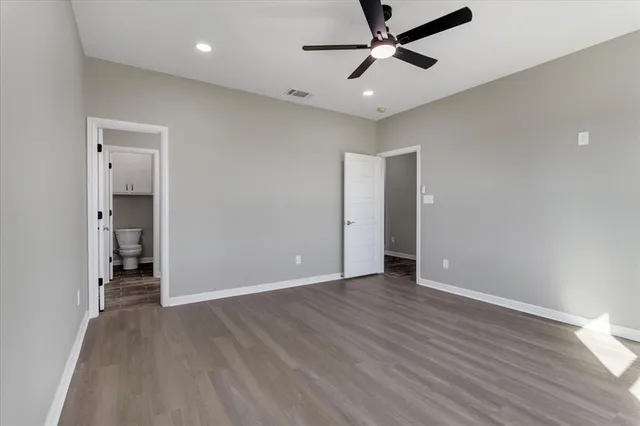 an empty room with wooden floor and a ceiling fan