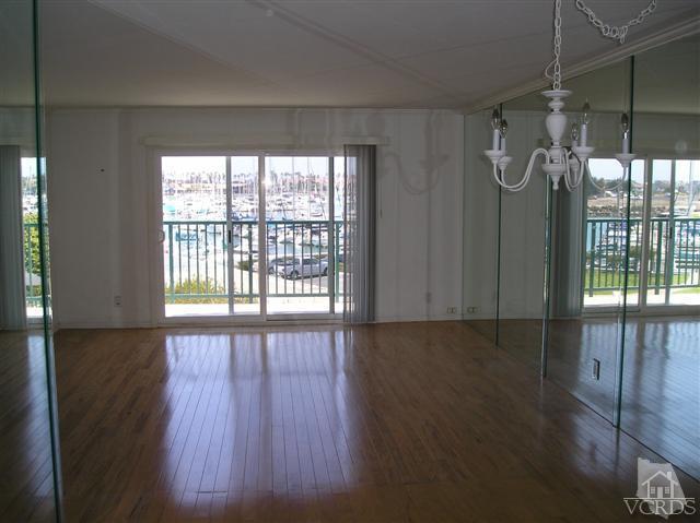 3101 Peninsula Road, Unit 218 Oxnard, CA 93035 - Photo 3 of 10 a view of an empty room with wooden floor and a window