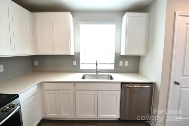 a kitchen with white cabinets and sink