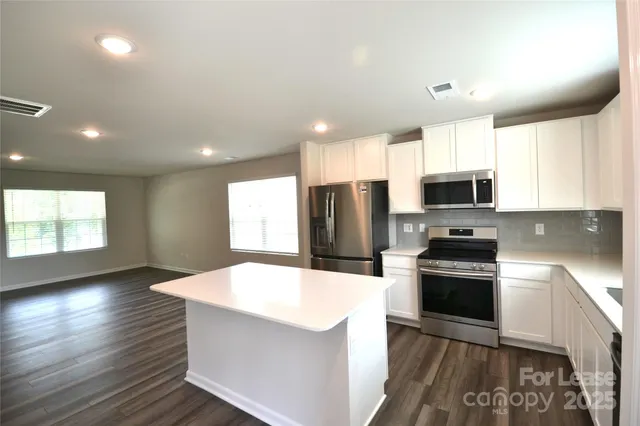 a kitchen with stainless steel appliances a microwave a stove a refrigerator sink cabinets and wooden floor