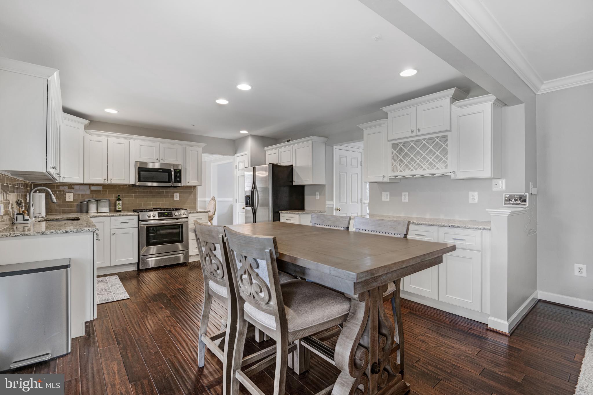 a kitchen with granite countertop a table chairs microwave and cabinets