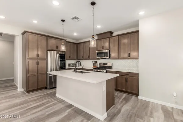 a kitchen with stainless steel appliances granite countertop a sink stove a refrigerator and a oven with wooden floor