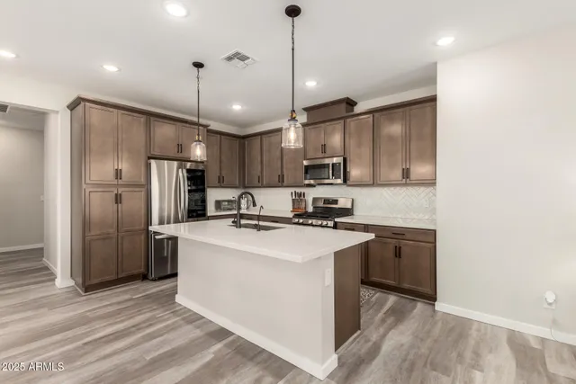 a kitchen with stainless steel appliances granite countertop a sink stove a refrigerator and a oven with wooden floor