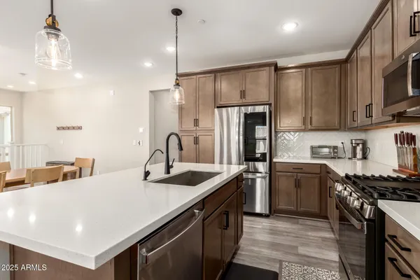 a kitchen with stainless steel appliances granite countertop a sink a stove and a refrigerator