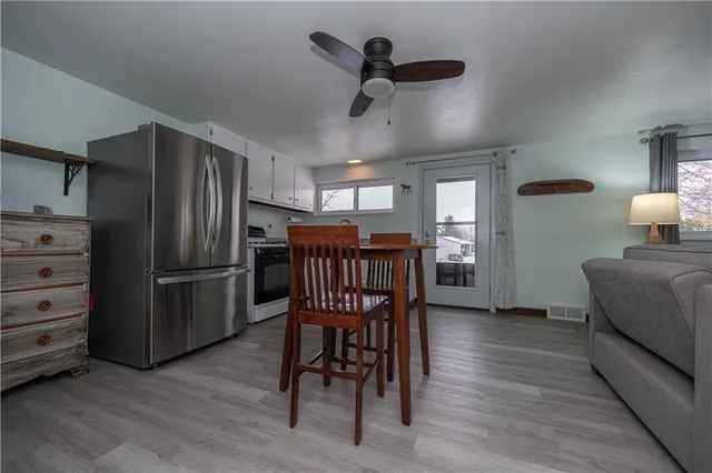 a kitchen with stainless steel appliances granite countertop a dining table chairs refrigerator and sink