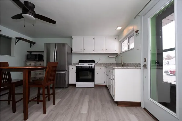 a kitchen with granite countertop wooden floors stainless steel appliances and sink