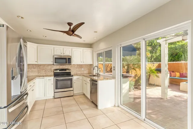 a kitchen with stainless steel appliances granite countertop a stove top oven a sink dishwasher a refrigerator with white cabinets and couches