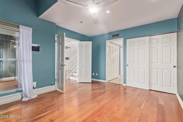 a view of an empty room with wooden floor and a bathroom