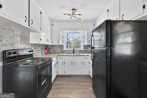 a kitchen with stainless steel appliances granite countertop a refrigerator a sink dishwasher a stove and white cabinets