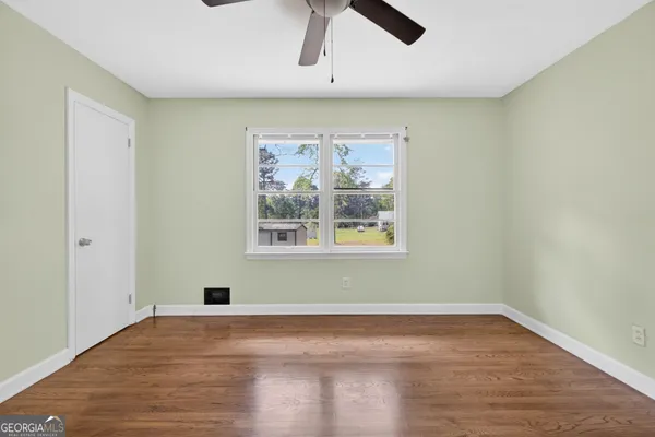 an empty room with wooden floor and windows