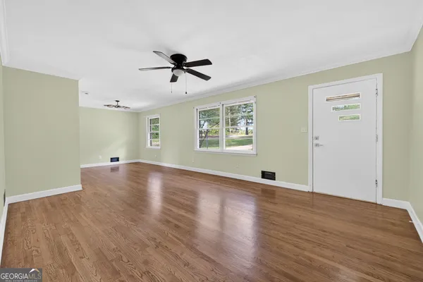 a view of empty room with wooden floor and fan