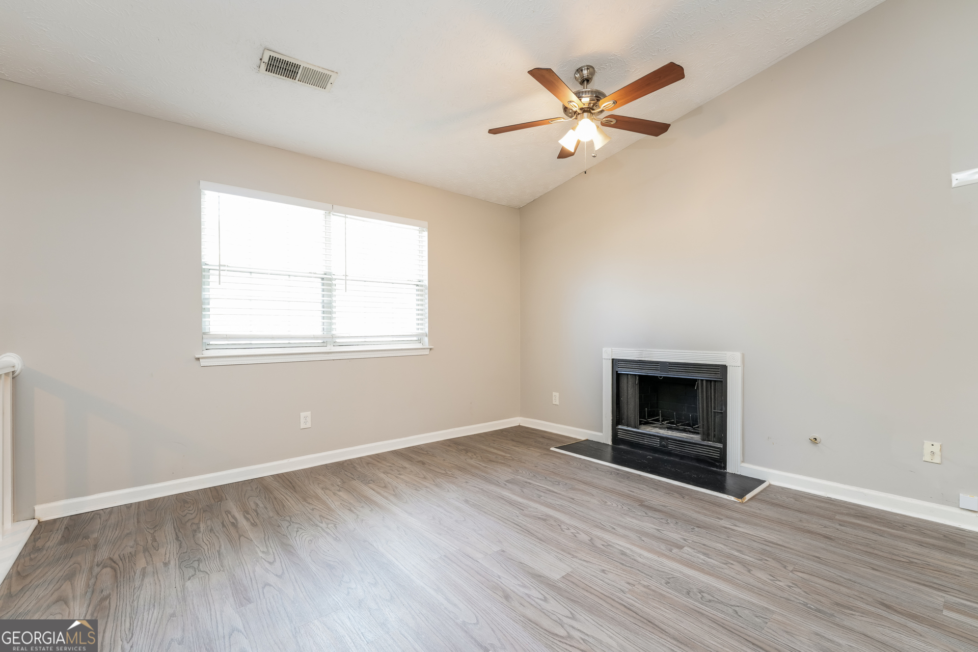 5591 Sapphire Spring Stone Mountain, GA 30088 - Photo 3 of 17 an empty room with wooden floor a ceiling fan and windows