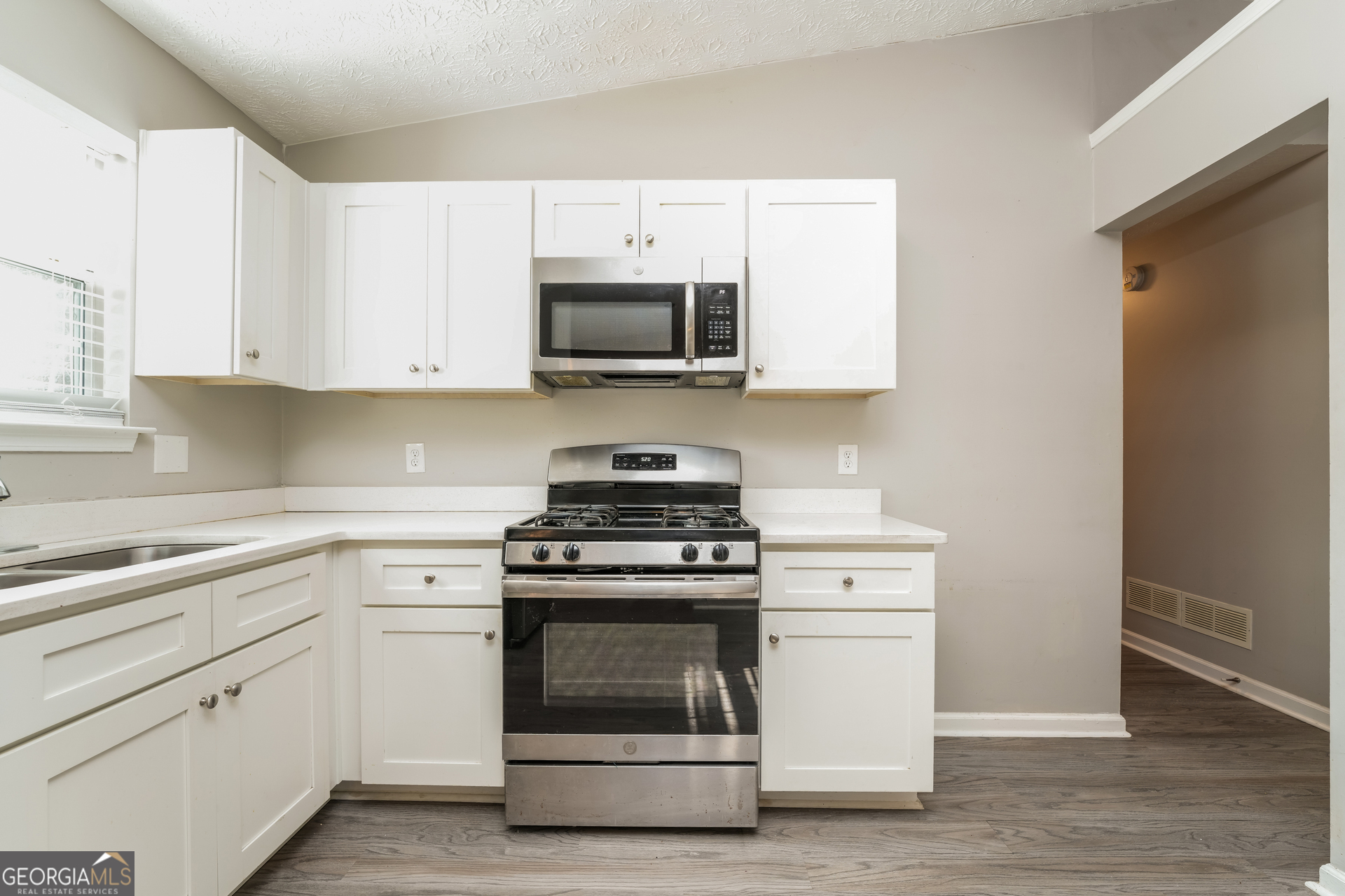 5591 Sapphire Spring Stone Mountain, GA 30088 - Photo 6 of 17 a kitchen with white cabinets and stainless steel appliances