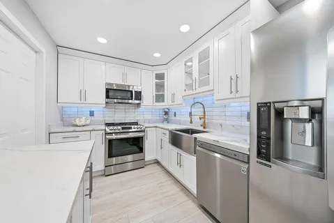 a kitchen with white cabinets and appliances