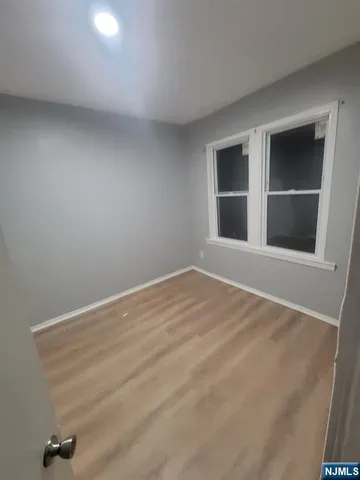 a view of an empty room with wooden floor and cabinet