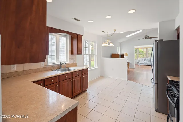 a large kitchen with stainless steel appliances a large counter top a refrigerator and a sink