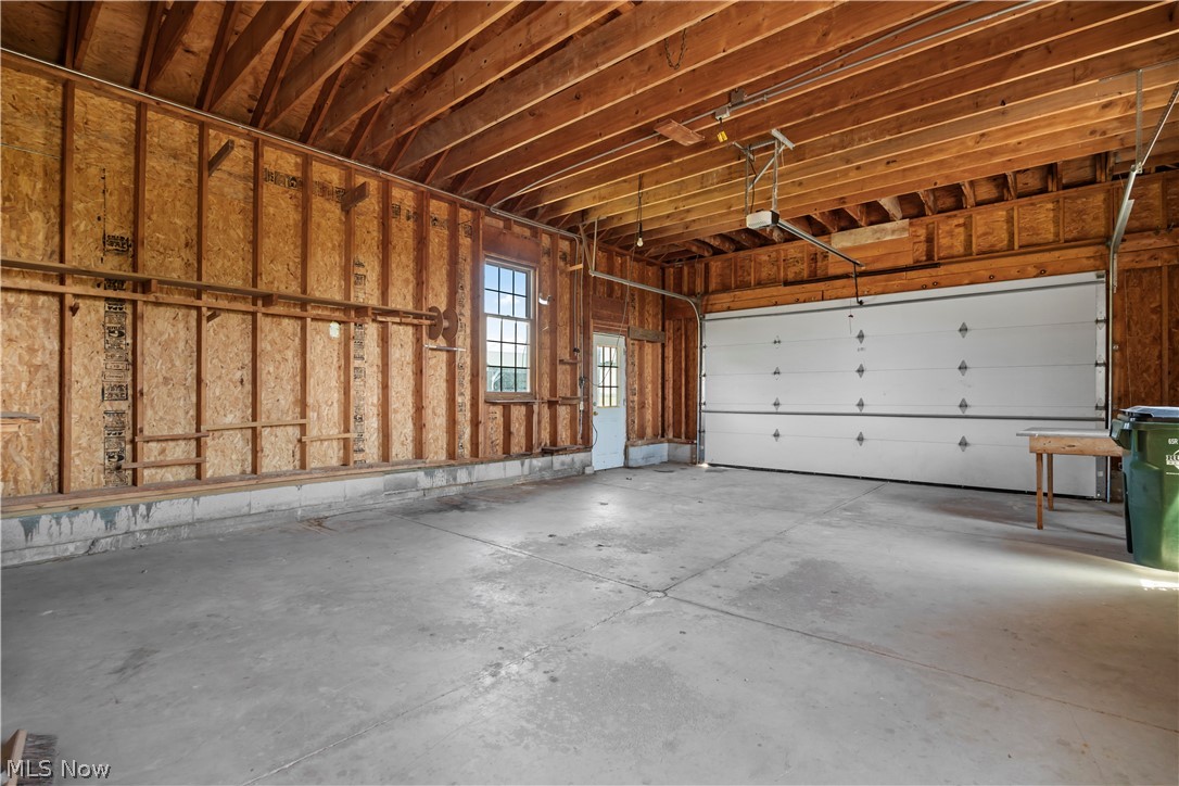 51488 Peck Wadsworth Road Wellington, OH 44090 - Photo 48 of 50 Spacious garage featuring a concrete floor, exposed wood ceiling beams, and a large overhead garage door
