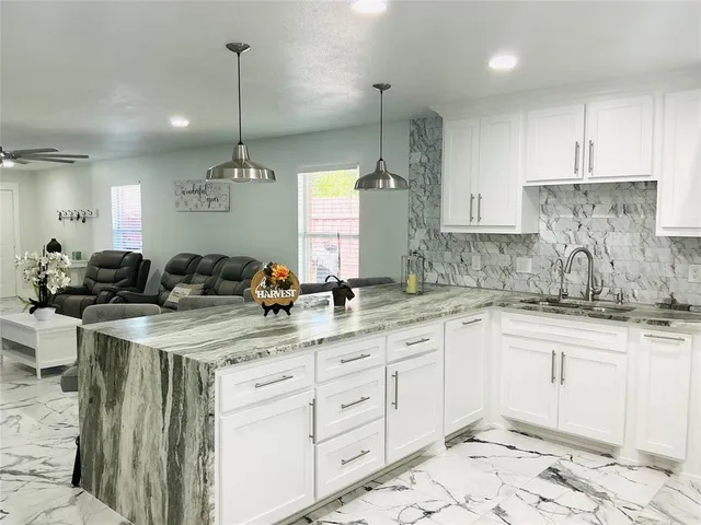 a kitchen with kitchen island granite countertop a sink a counter space appliances and cabinets