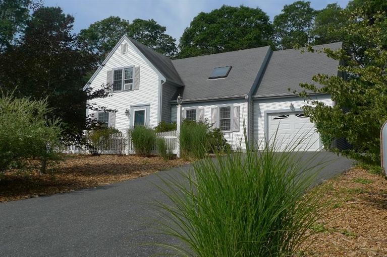 a view of a white house next to a yard with plants and trees