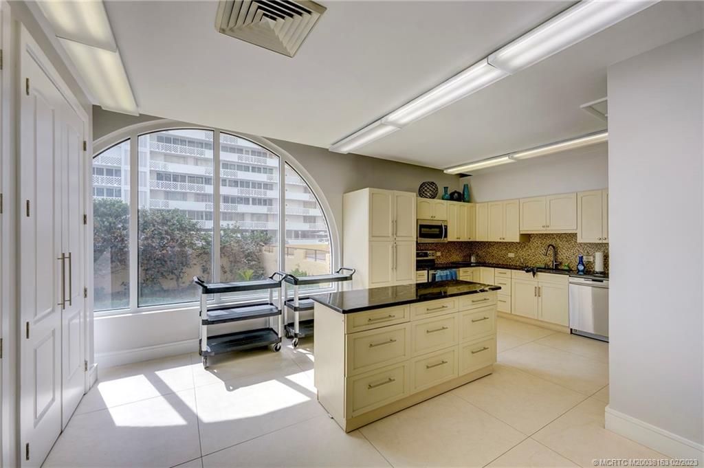 1180 South Ocean Boulevard, Unit 8B Boca Raton, FL 33432 - Photo 19 of 62 a kitchen with granite countertop a stove a sink and white cabinets with wooden floor