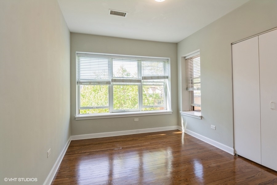 6853 South Ridgeland Avenue, Unit 402 Chicago, IL 60649 - Photo 4 of 6 an empty room with wooden floor and windows