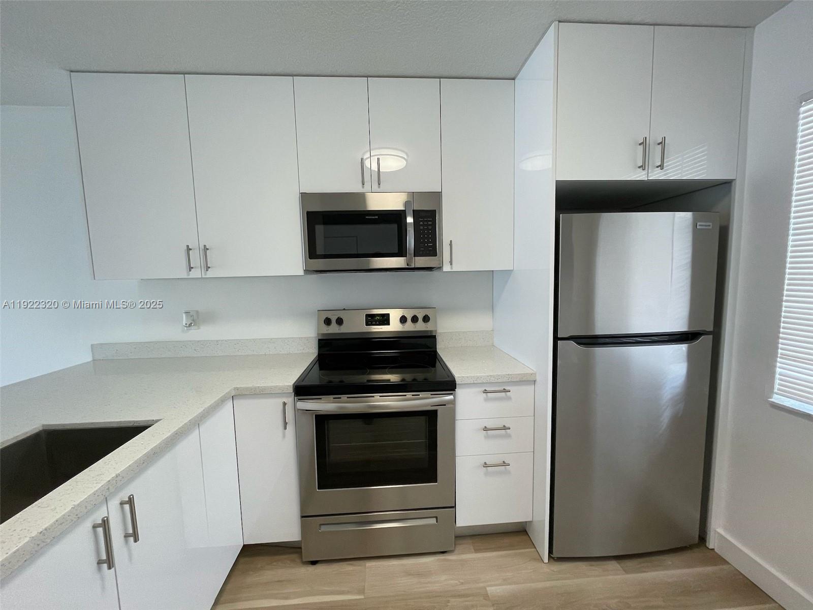 8700 Sherman Circle North, Unit 501 Miramar, FL 33025 - Photo 6 of 14 a kitchen with white cabinets and stainless steel appliances