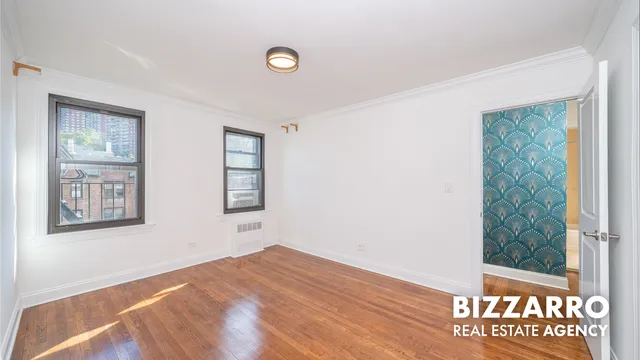 a view of a bedroom with wooden floor and windows