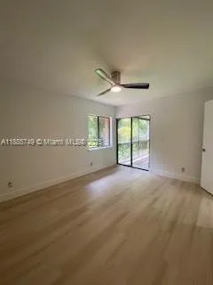 an empty room with windows and ceiling fan