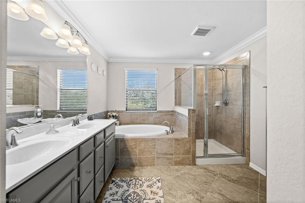 4754 Abaca Circle Naples, FL 34119 - Photo 21 of 46 a bathroom with a double vanity sink toilet mirror and bathtub