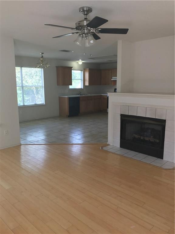 8337 Alvin High Lane Austin, TX 78729 - Photo 3 of 14 Unfurnished living room featuring light wood-style flooring, ceiling fan, and a tile fireplace