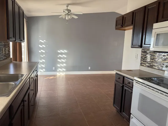 a kitchen with kitchen island a counter space a sink appliances and cabinets