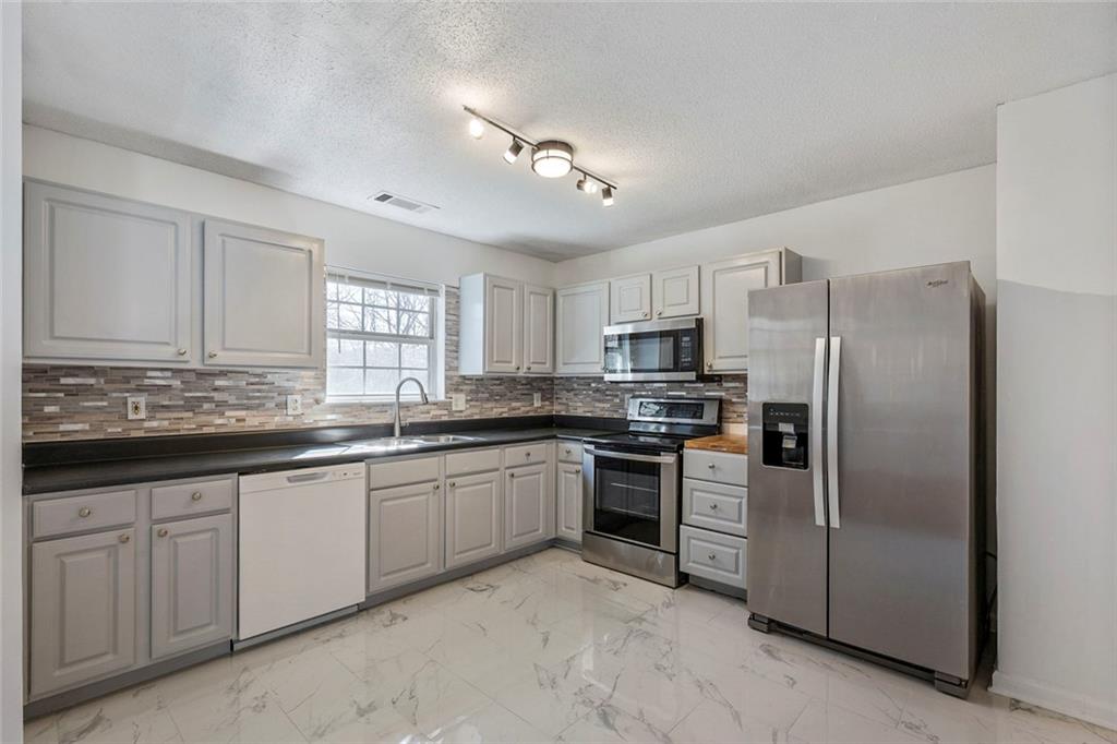 6132 Christopher Terrace Rex, GA 30273 - Photo 12 of 40 a kitchen with granite countertop a refrigerator sink and cabinets