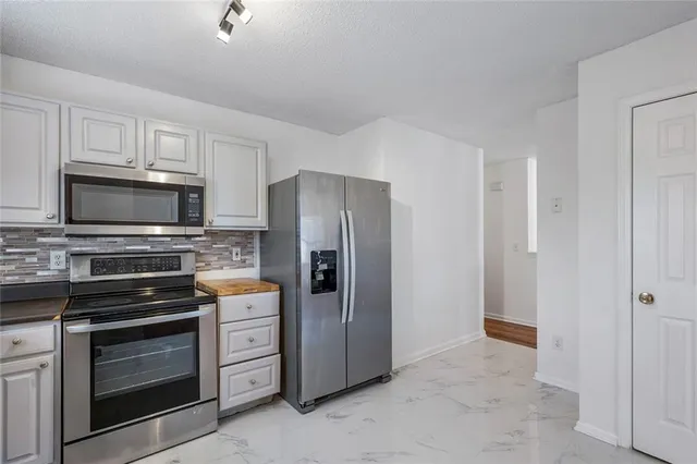 a kitchen with white cabinets and stainless steel appliances