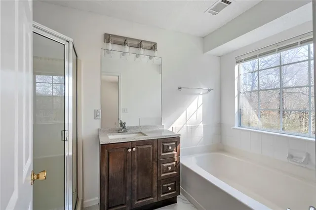 a bathroom with a granite countertop sink a bathtub and a shower