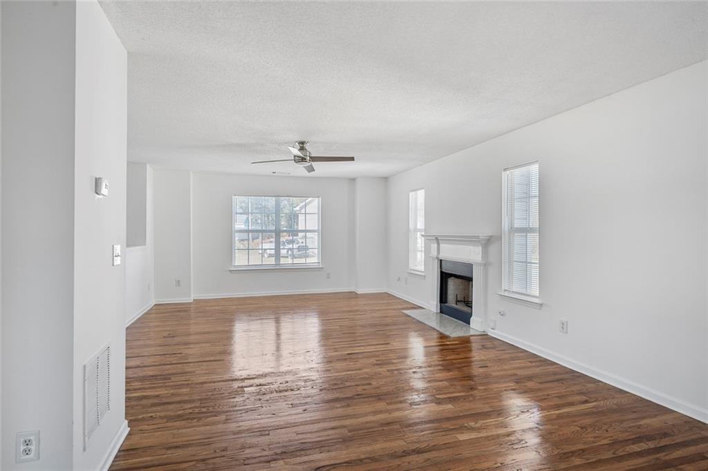 6132 Christopher Terrace Rex, GA 30273 - Photo 7 of 40 an empty room with wooden floor fireplace and windows