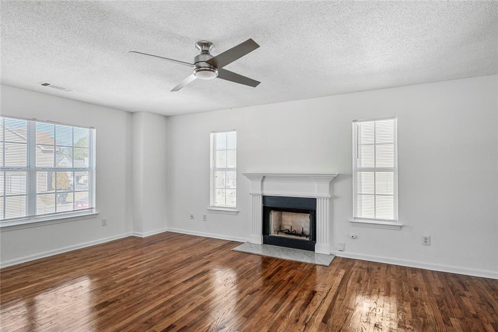 6132 Christopher Terrace Rex, GA 30273 - Photo 10 of 40 an empty room with windows fireplace and wooden floor