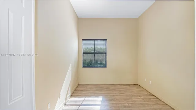 a view of an empty room with wooden floor and a window
