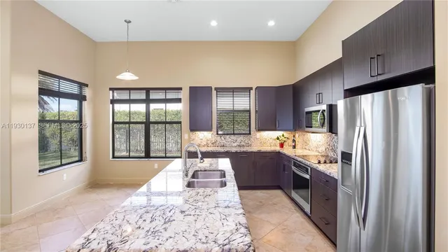 a large kitchen with stainless steel appliances granite countertop a refrigerator oven stove a sink and dishwasher with wooden floor