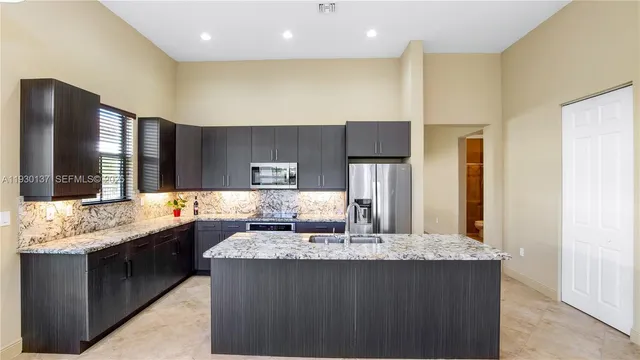 a kitchen with kitchen island granite countertop wooden cabinets and a refrigerator