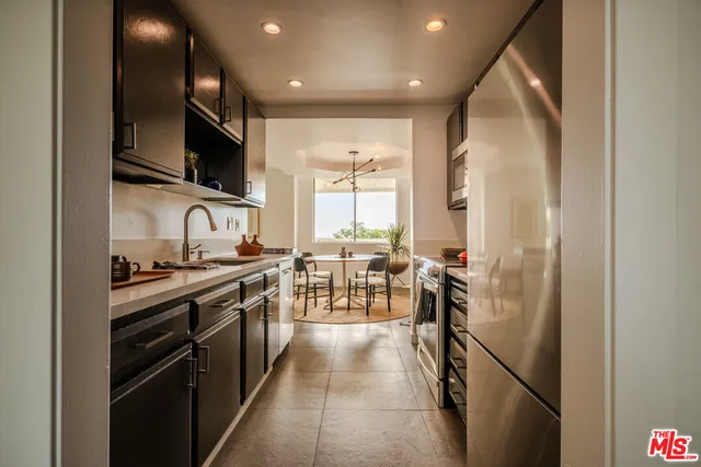 a kitchen with stainless steel appliances a stove top oven a sink a dining table and chairs