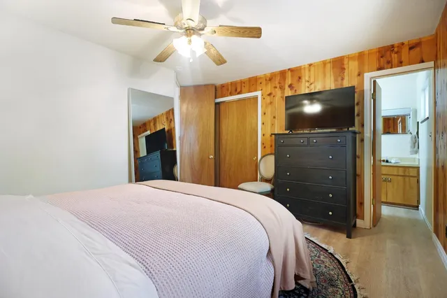 a bedroom with a bed and a flat tv screen on dresser