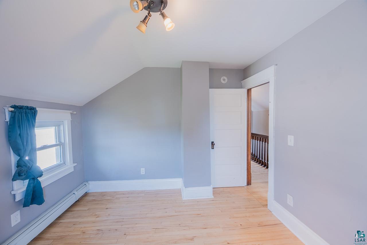 508 10th Street South Virginia, MN 55792 - Photo 24 of 43 Room featuring wood-finish flooring, light gray walls, a window with white trim, and a white interior door