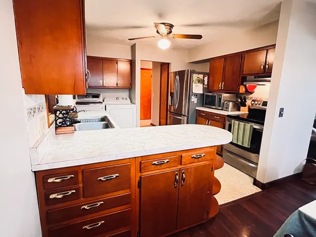 a kitchen with stainless steel appliances granite countertop a refrigerator a stove and a sink with wooden cabinets