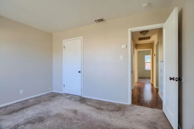 a view of a hallway with wooden floor and a bathroom