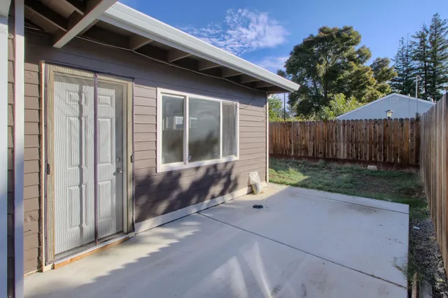 a view of backyard with small cabin and wooden fence