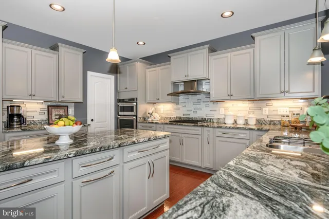 a spacious bedroom with a bed a dresser and a chandelier